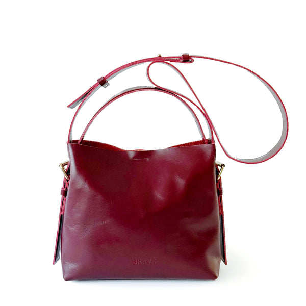Cartera de cuero burdeos de silueta sobria con asas regulables, modelo Paula marca _BRAVA, vista frontal.