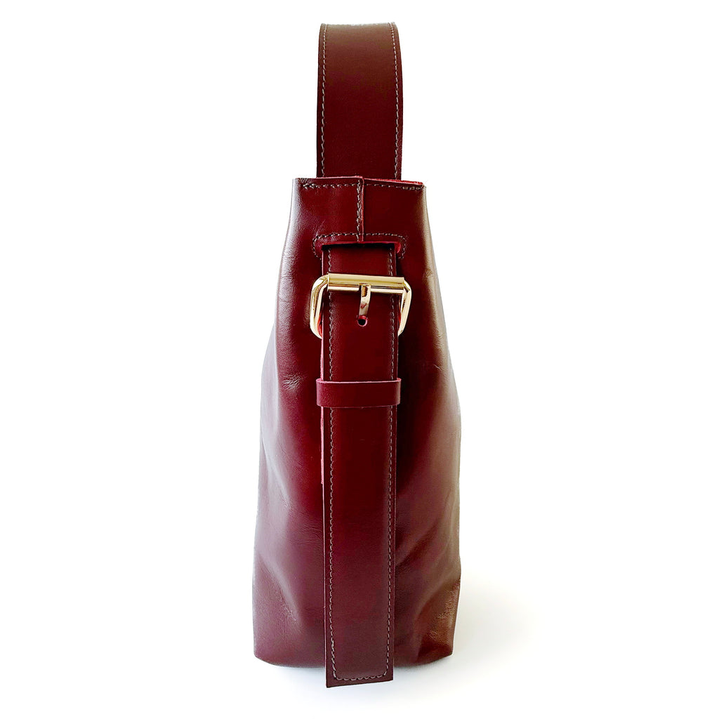 Cartera de cuero burdeos de silueta sobria con asas regulables, modelo Paula marca _BRAVA, vista lateral.